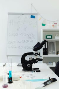 Modern lab setup with a microscope and chemical formulas on a whiteboard, ideal for science education.